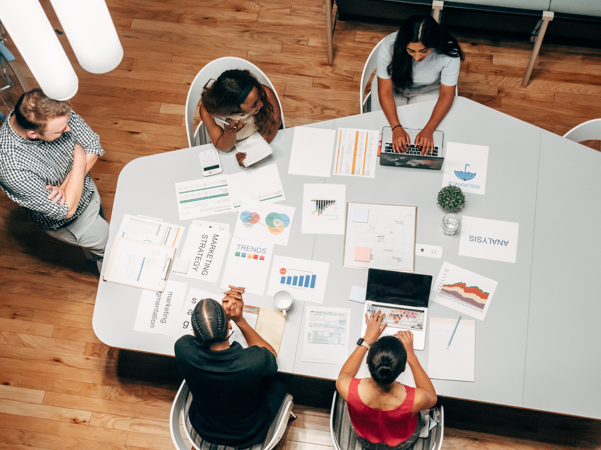 Overhead view of a marketing team working through campaign reports around a table.